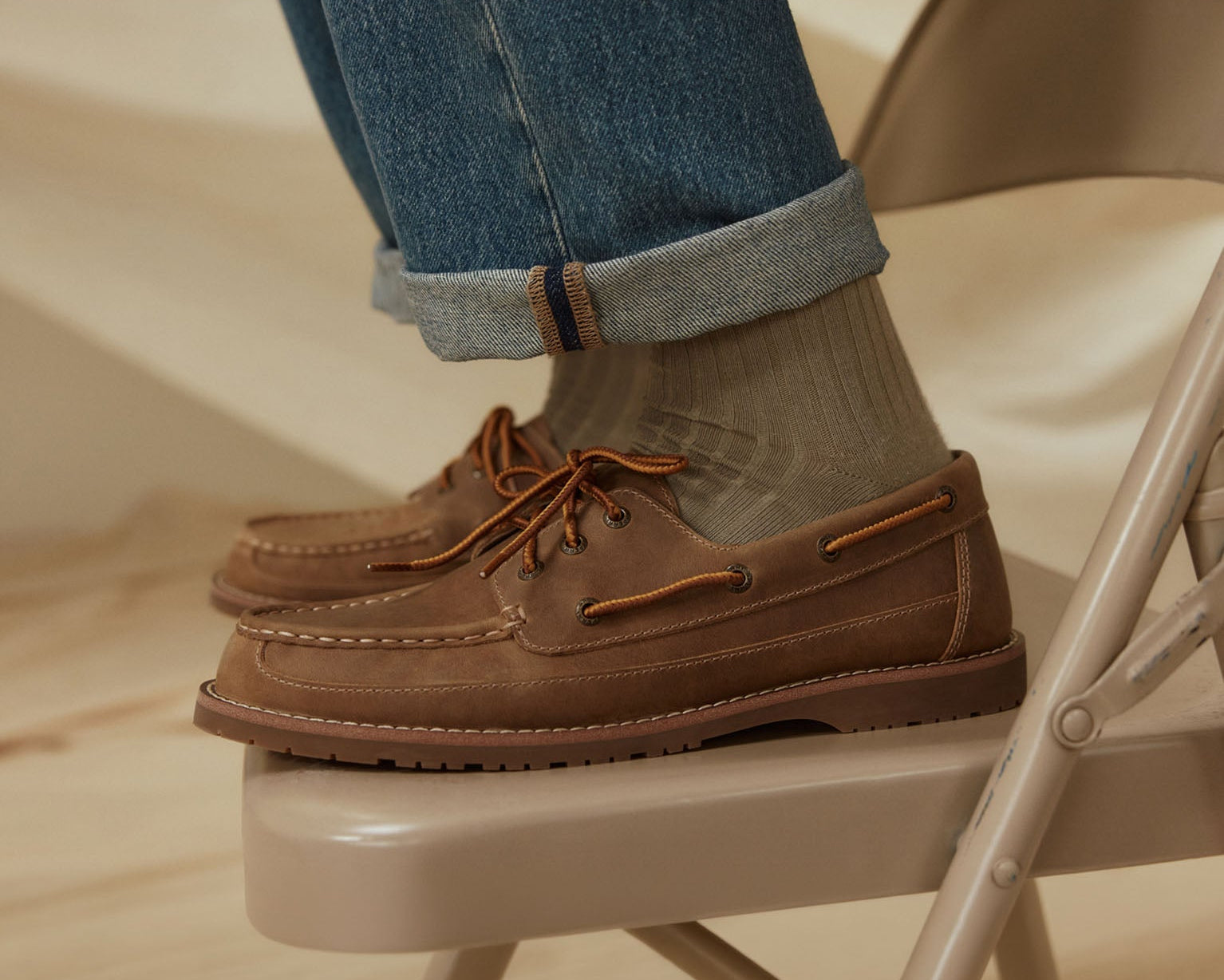 A pair of men's tan boat shoes on a chair